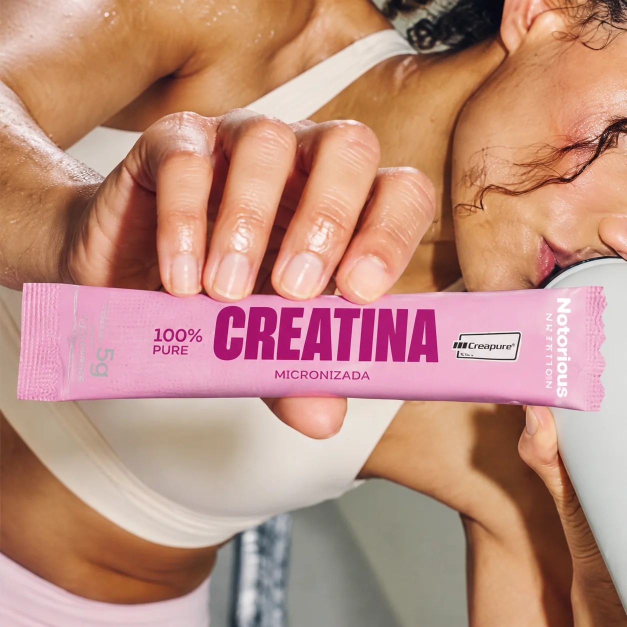 Atleta segurando um sachê rosa de creatina Notorious Nutrition