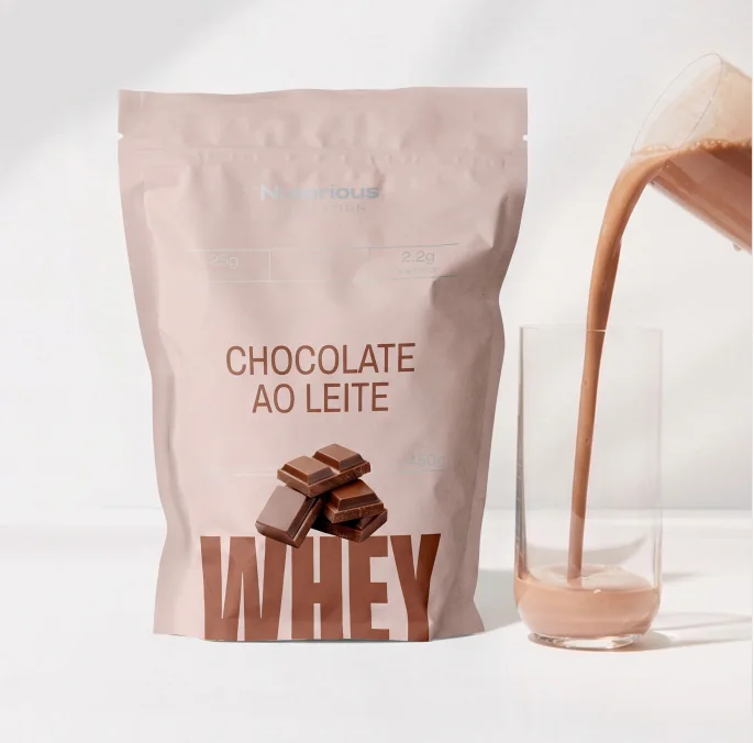 Whey de chocolate ao leite Notorious Nutrition ao lado de um copo com bebida de chocolate sendo servido